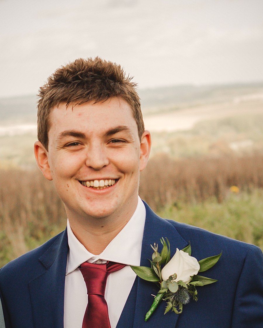 Oliver Porter, founder of Swarm ICT, smiling in a navy suit with the Wiltshire countryside behind him